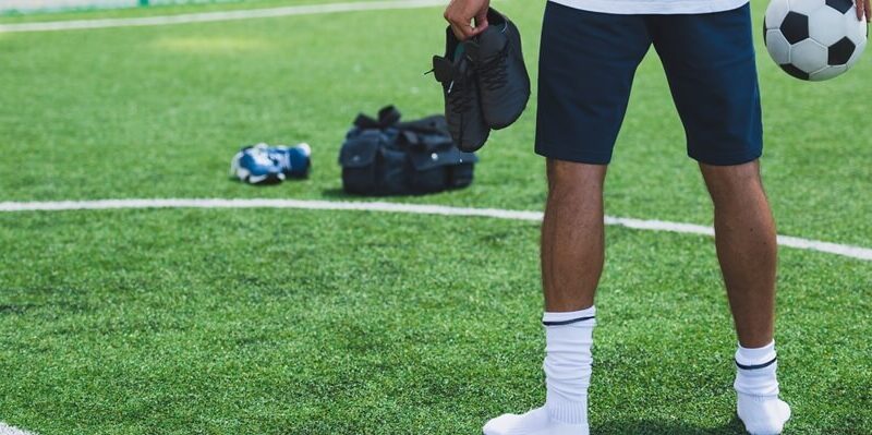 5-a-side football player holding a pair of astro boots.