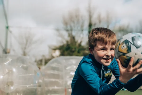 a young boy holding a soccer ball on a field