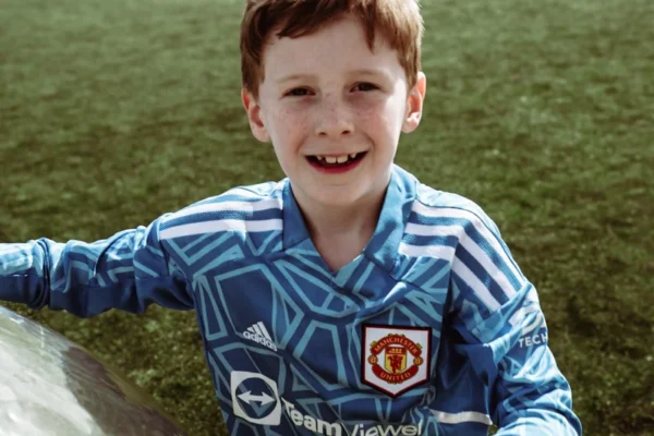 a young boy sitting in the grass with a soccer ball