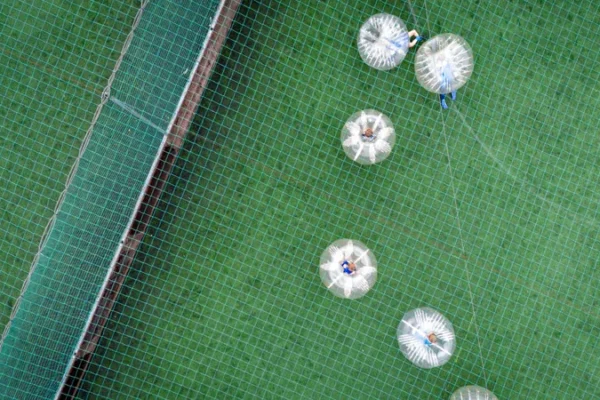 a group of people riding in inflatable balls on a green field